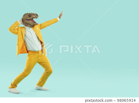 Crazy man in yellow suit and funny dinosaur mask dancing on turquoise copy space background 98065914