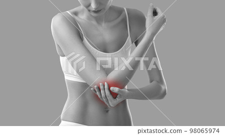 Young woman who is feeling elbow pain due to arm injury is touching painful area 98065974