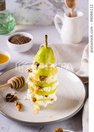 Layers of pear, ricotta with walnut poured with honey on a plate. Vitamin nutrition. Vertical view 98066112
