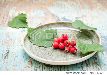 Hawthorn branch with berries and leaves on a plate on a rustic background 98066326