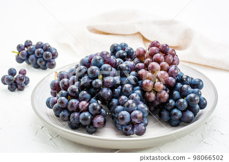 Berries of ripe blue grapes on a plate on a table Berries of ripe blue grapes on a plate on a table 98066502