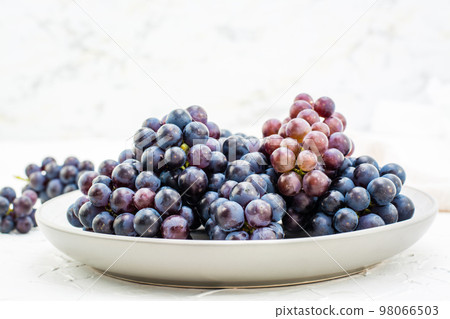 Berries of ripe blue grapes on a plate on a table Berries of ripe blue grapes on a plate on a table 98066503