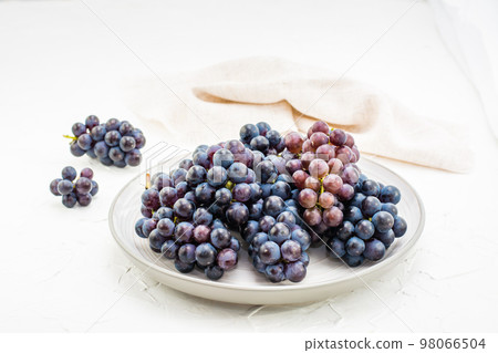 Berries of ripe blue grapes on a plate on a table. Harvesting in autumn 98066504