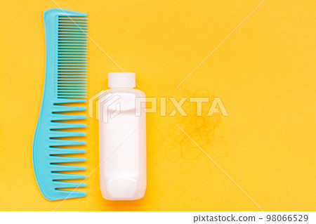 Comb, bottle with balm and a hank of fallen hair on a yellow background. Concept - hair loss. Top View Comb, bottle with balm and a hank of fallen hair on a yellow background. Concept - hair loss. Top View 98066529