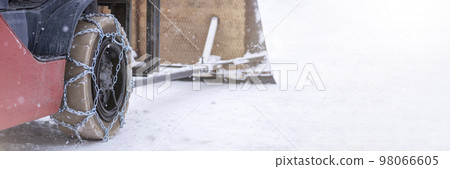 Tractor wheel with chain. Tractor or loader on a slippery snowy road. Loaders drive on snow with anti-skid chains. 98066605