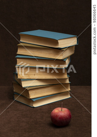 Still life with a stick of old books and an apple on the table Still life with a stick of old books and an apple on the table 98066645