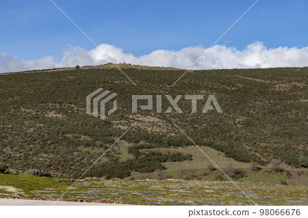 Mountains. Green mountains in the municipality of El Atazar, north of the Community of Madrid. Sunny day with air and clouds decorating the sky. Iron decoration on the green grass. Farmer. Donkey. Mountains. Green mountains in the municipality of El Atazar, north of the Community of Madrid. Sunny day with air and clouds decorating the sky. Iron decoration on the green grass. Farmer. Donkey. 98066676