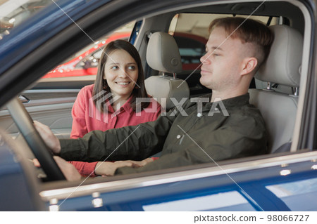 couple of man and woman buy car at dealership. happy husband and wife are holding keys to new auto. couple of man and woman buy car at dealership. happy husband and wife are holding keys to new auto. 98066727