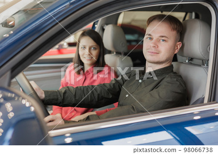 couple of man and woman buy car at dealership. happy husband and wife are holding keys to new auto. couple of man and woman buy car at dealership. happy husband and wife are holding keys to new auto. 98066738