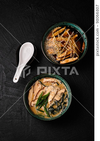 Two bowls of Asian soup on black background 98066807