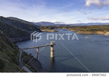 Reservoir. Prey. Dam located in the Atazar, north of the Community of Madrid. Damned water next to some green and pink mountains. Horizontal Photography 98067002