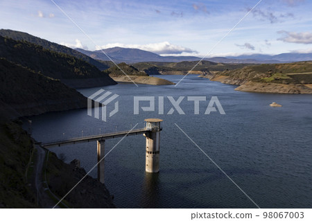 Reservoir. Prey. Dam located in the Atazar, north of the Community of Madrid. Damned water next to some green and pink mountains. Horizontal Photography Reservoir. Prey. Dam located in the Atazar, north of the Community of Madrid. Damned water next to some green and pink mountains. Horizontal Photography 98067003