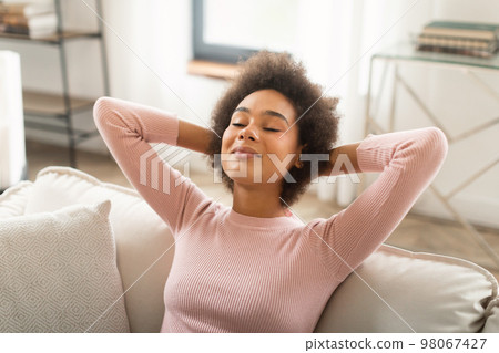 Glad happy young mixed race woman resting on sofa with closed eyes, enjoy peace, silence and free time Glad happy young mixed race woman resting on sofa with closed eyes, enjoy peace, silence and free time 98067427