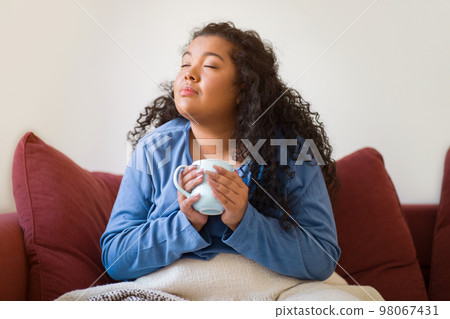 Delighted chubby woman sitting on couch drinking hot tea 98067431