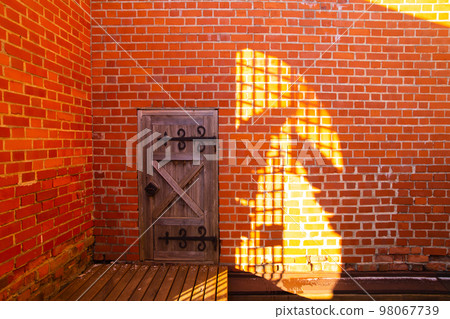 A door and part of brick wall with shadows inside a castle 98067739