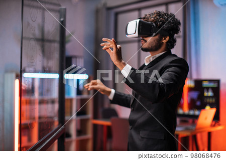 Young male company workers wearing VR headset while having meeting at office room. 98068476