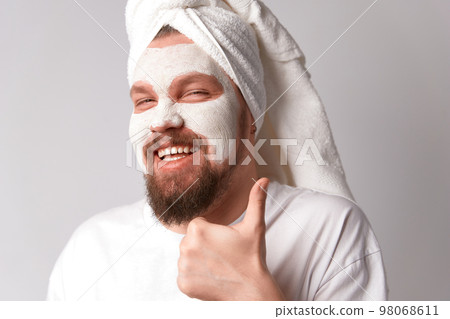 Man in white tshirt apply facial mask stand against white background. Self care morning spa procedure Man in white tshirt apply facial mask stand against white background. Self care morning spa procedure 98068611