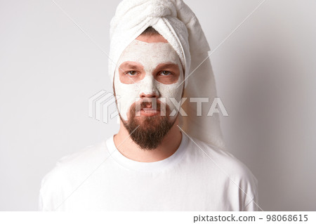 Man in white tshirt apply facial mask stand against white background. Self care morning spa procedure Man in white tshirt apply facial mask stand against white background. Self care morning spa procedure 98068615