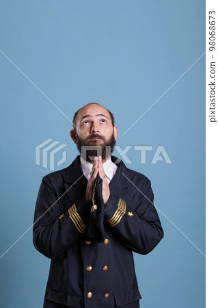 Airline pilot in uniform praying to gods, looking upwards, standing with folded hands gesture. Religious plane captain pleasing, aviator worshiping before flight, praising Airline pilot in uniform praying to gods, looking upwards, standing with folded hands gesture. Religious plane captain pleasing, aviator worshiping before flight, praising 98068673