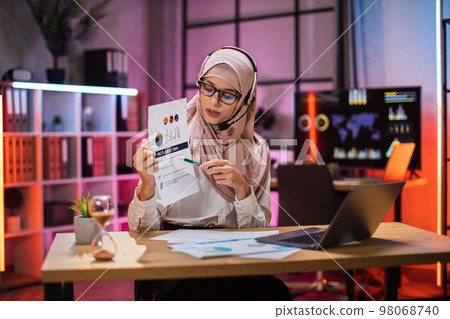 Experienced financial expert office worker muslim woman in hijab working on laptop 98068740