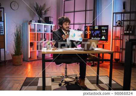 Experienced financial expert office worker in suit working on laptop, showing paper report 98068824