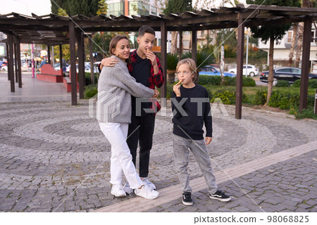 Family in a summer park. Mother and her sons with ice cream in the city. 98068825