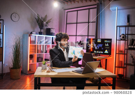 Handsome successful qualified bearded office manager in suit wears headset during online video call Handsome successful qualified bearded office manager in suit wears headset during online video call 98068828