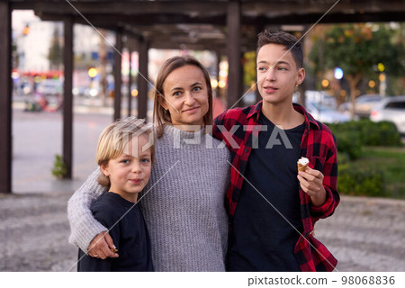 Family in a summer park. Mother and her sons with ice cream in the city. Family in a summer park. Mother and her sons with ice cream in the city. 98068836