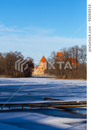 Trakai, Lithuania - 01 08 22: Island Castle in winter in sunny weather, lake covered with ice 98068916
