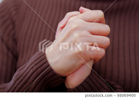 woman folding her hands in front of her chest woman folding her hands in front of her chest 98069400