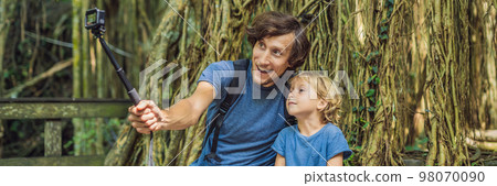 Dad and son travelers discovering Ubud forest in Monkey forest, Bali Indonesia. Traveling with children concept. Videoblog, Selfie. BANNER, long format Dad and son travelers discovering Ubud forest in Monkey forest, Bali Indonesia. Traveling with children concept. Videoblog, Selfie. BANNER, long format 98070090