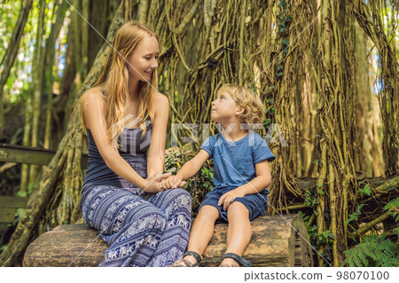 Mom and son travelers discovering Ubud forest in Monkey forest, Bali Indonesia. Traveling with children concept Mom and son travelers discovering Ubud forest in Monkey forest, Bali Indonesia. Traveling with children concept 98070100