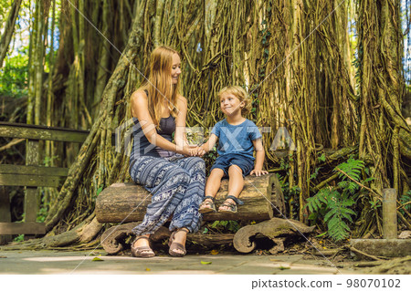 Mom and son travelers discovering Ubud forest in Monkey forest, Bali Indonesia. Traveling with children concept 98070102