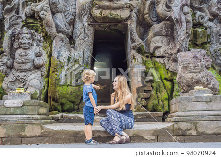 Mom and son are tourists in Old Hindu temple of Goa Gajah near Ubud on the island of Bali, Indonesia. Travel in Bali with children concept Mom and son are tourists in Old Hindu temple of Goa Gajah near Ubud on the island of Bali, Indonesia. Travel in Bali with children concept 98070924