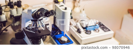 A sample preparation table in a laboratory with an optical microscope, ultrasonic cutter system and precision micrometer grinder polishing machine BANNER, long format 98070946