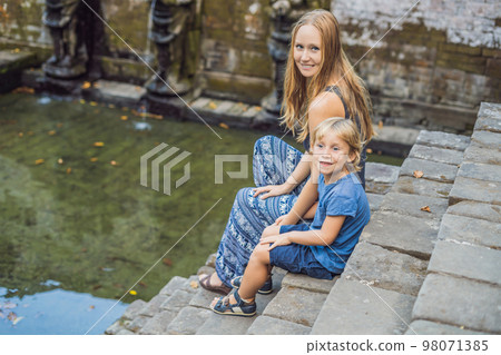Mom and son are tourists in Old Hindu temple of Goa Gajah near Ubud on the island of Bali, Indonesia. Travel in Bali with children concept Mom and son are tourists in Old Hindu temple of Goa Gajah near Ubud on the island of Bali, Indonesia. Travel in Bali with children concept 98071385