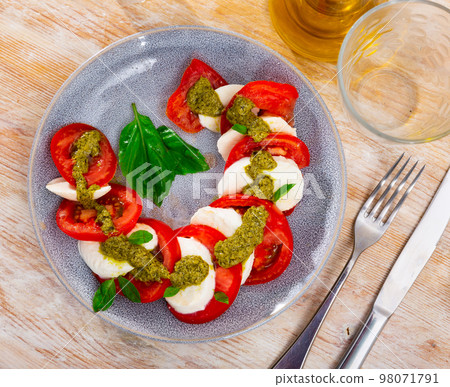 Traditional snack of Italian cuisine is Caprese with basil and Pesto sauce 98071791