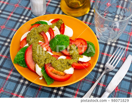 Caprese salad with basil and pesto sauce served on plate Caprese salad with basil and pesto sauce served on plate 98071829