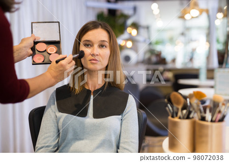 Hand of makeup master applying tonal foundation on face of woman Hand of makeup master applying tonal foundation on face of woman 98072038