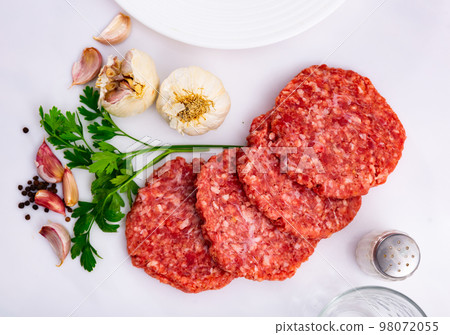 Cooking ingredients, raw burger cutlets on board Cooking ingredients, raw burger cutlets on board 98072055
