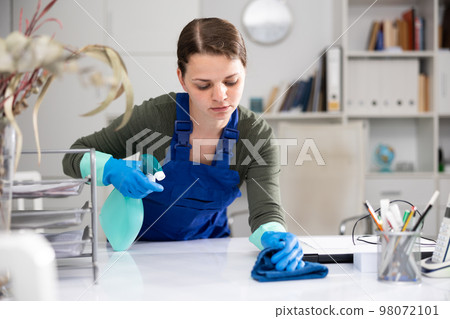 Woman cleaner polishing table in office Woman cleaner polishing table in office 98072101