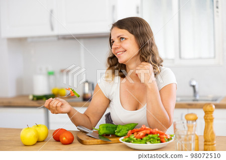 Portrait of positive woman eating salad at home 98072510