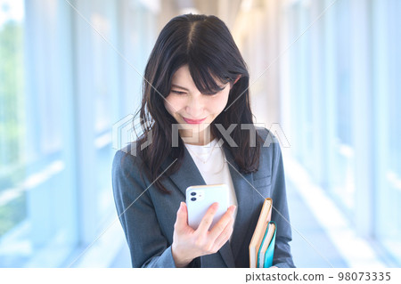在辦公室走廊裡看智能手機的年輕西裝女商人 98073335
