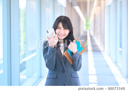 在辦公室走廊裡看智能手機的年輕西裝女商人 98073348