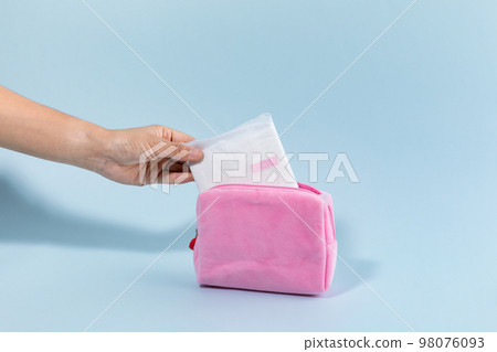 woman menstrual products_taking out the sanitary pad from pouch 98076093
