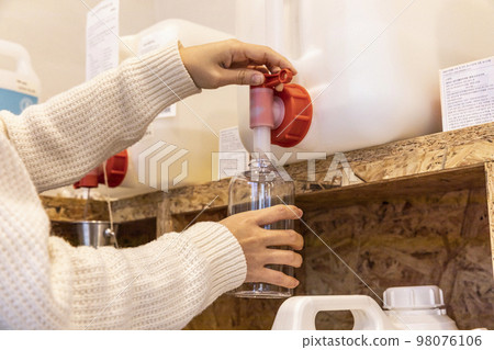 eco friendly habits hand gesture_refilling detergent at zero waste shop 98076106