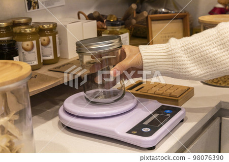 eco friendly habits hand gesture_refilling and weighing at zero waste shop 98076390