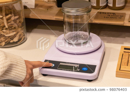 eco friendly habits hand gesture_refilling and weighing at zero waste shop 98076403
