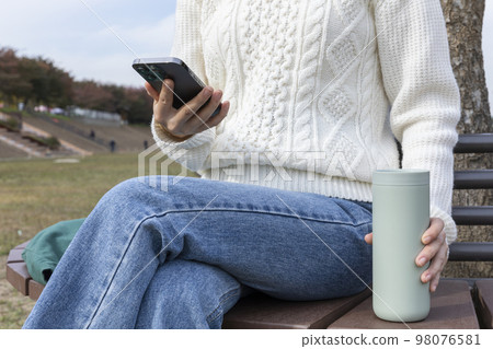 eco friendly habits hand gesture_using tumbler and cellphone 98076581