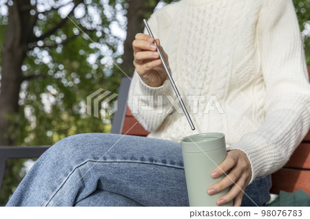 eco friendly habits hand gesture_sticking a stainless steel straw in a tumbler eco friendly habits hand gesture_sticking a stainless steel straw in a tumbler 98076783